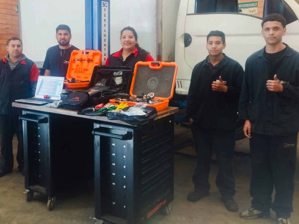 Equipe da DMK Eletrodiesel ao lado da bancada de ferramentas