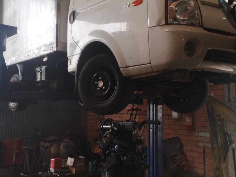 Veículo no elevador com o motor retirado e apoiado no chão da oficina